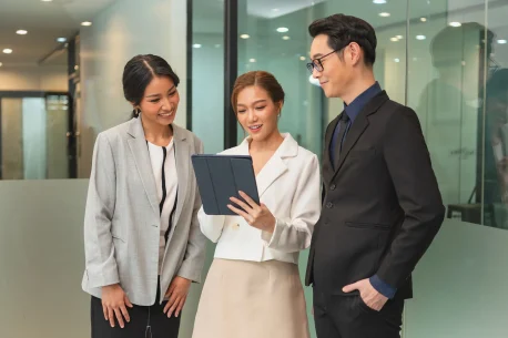 smiling-asian-businesswoman-showing-tablet-her-manager-talking-office 1